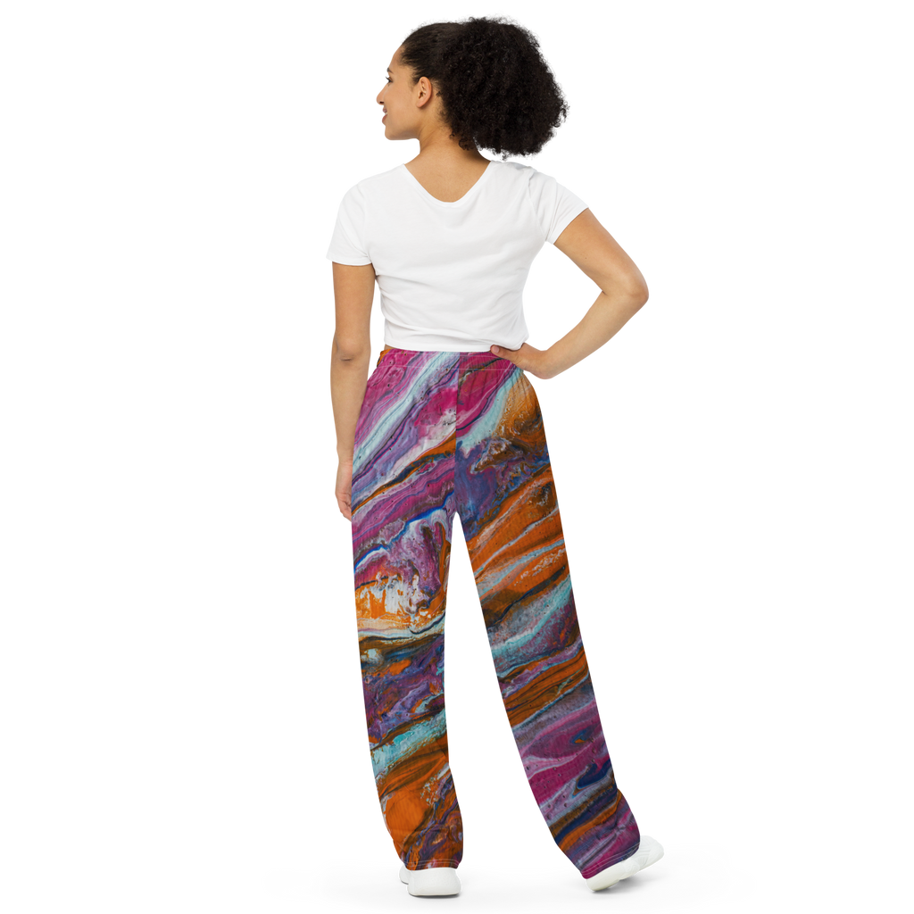 Unisex wide-leg pants featuring a vibrant paint pour design by Yurmaze in pink, orange, and blue tones, worn as comfortable lounge trousers.