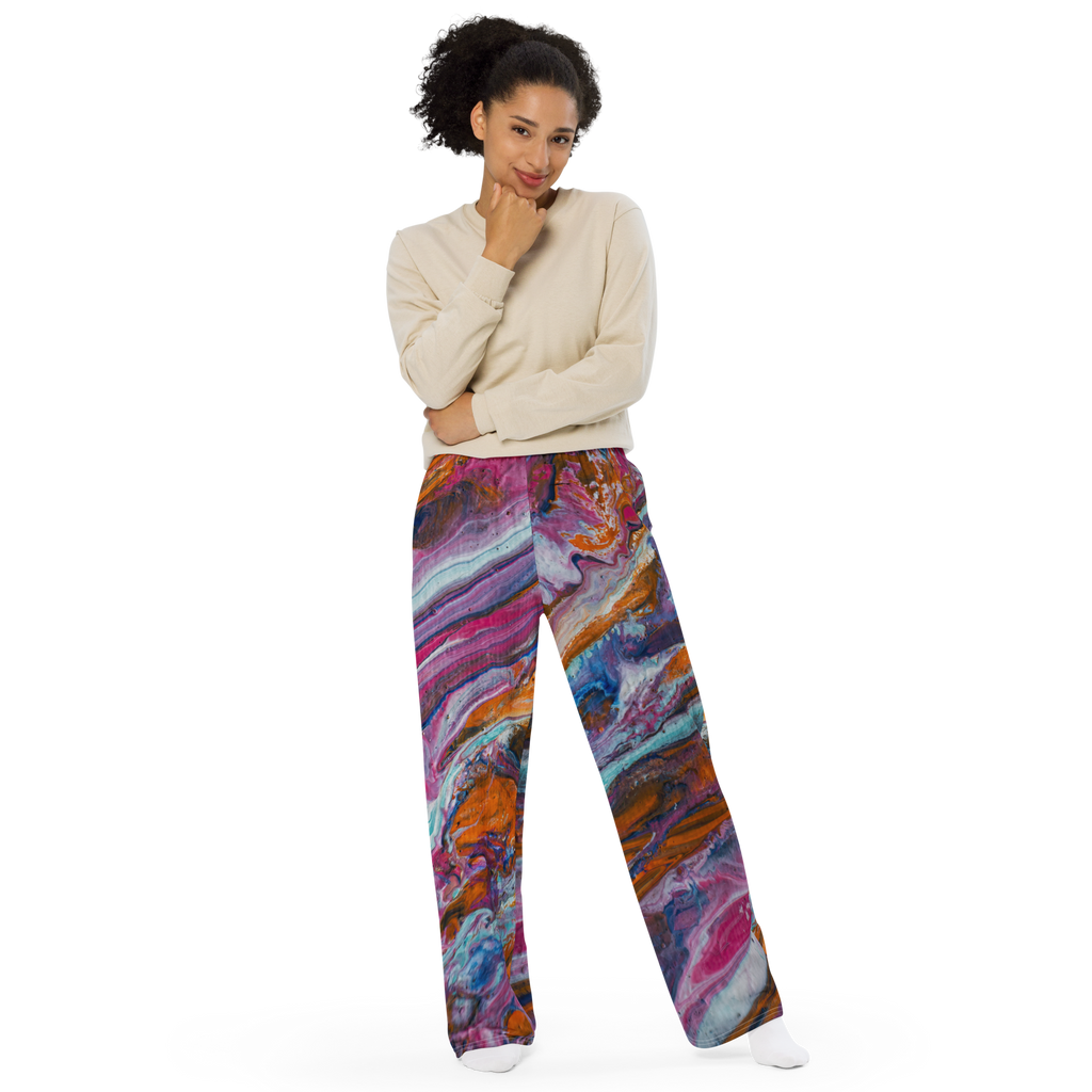 Unisex wide-leg pants featuring a vibrant paint pour design by Yurmaze in pink, orange, and blue tones, worn as comfortable lounge trousers.