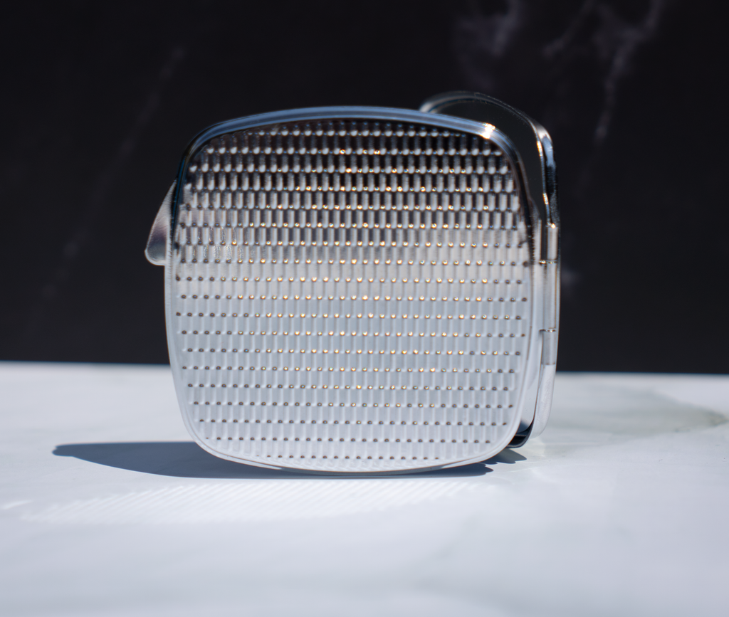 Square personalised compact mirror with abstract paint pour artwork on a metal case, displayed from the back on a marble background.